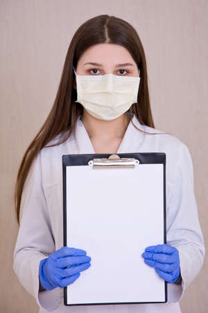 Female doctor wearing protection face mask holding notes. Free copy space. Covid-19 concept.の写真素材