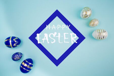 Happy Easter card with copy space. Frame with blue and white eggs with gold patterns on blue background. Lettering Happy Easterの写真素材