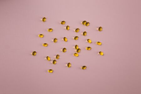 Vitamin d capsules on a pink background. Close up top view