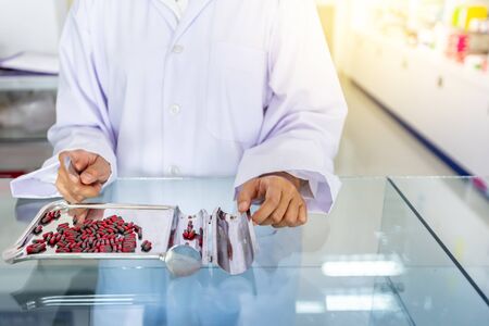 Pharmacist is counting medical pills on stainless steel tray at drugstore. Health care and medical concept.の写真素材