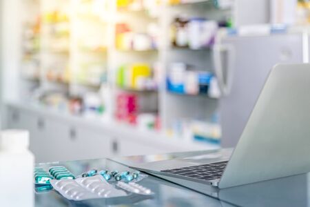 Medicine and computer on payment counter with blurred medicines shelves background. Healthcare, medical and pharmacy concept.の写真素材