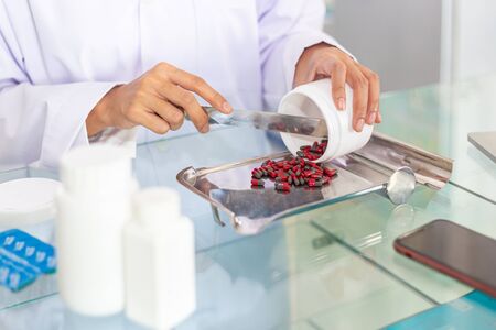 Pharmacist is pouring the medicine out of the medicine bottle into the pill counting tray. Health care and medical concept.の写真素材