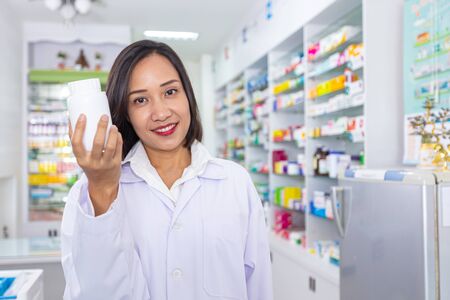 Pharmacist holding medicine bottle in pharmacy. Health care and medical concept.の写真素材