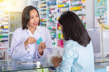 Female pharmacist counseling customer about contraceptive pill usage in modern pharmacy. Medicine, pharmaceutics, health care and people concept.の写真素材