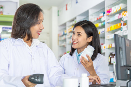 Two female pharmacists scanning medicine bottle by scanner in pharmacy.の写真素材