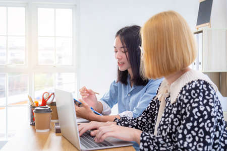 Young office workers discussing paperwork and information on a laptop computer. Business people in office and teamwork concept.の写真素材