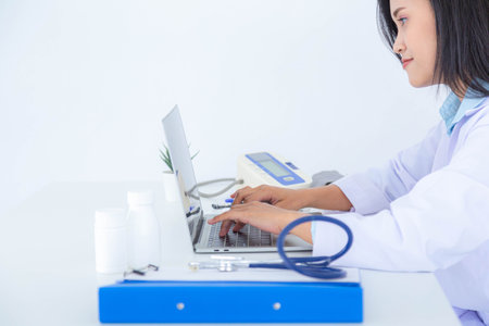 Female doctor or pharmacist working on laptop computer at her desk.の写真素材
