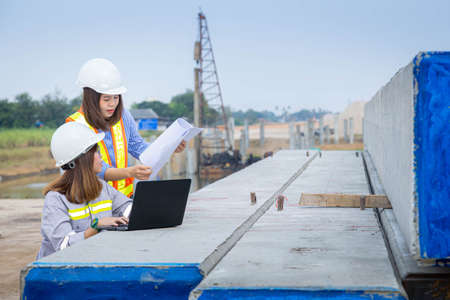 Two female architect leader working with laptop and blueprints at construction site or building site.の写真素材