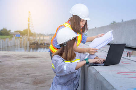 Two female architect leader working with laptop and blueprints at construction site or building site.の写真素材