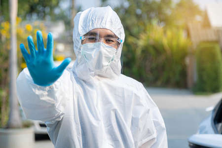 Male doctor in a protective gown and mask shows a stop sign on road.の写真素材