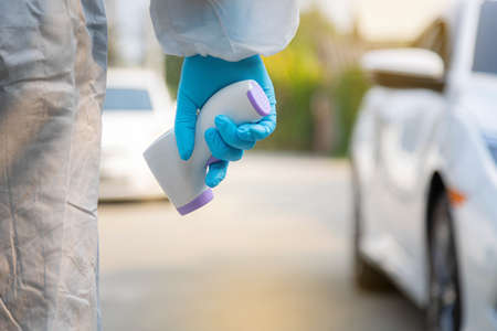 Medical staff with PPE use infrared thermometer gun on road.の写真素材
