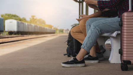 Male and female tourists wait for the train at the train station. On the left is an empty space.の写真素材