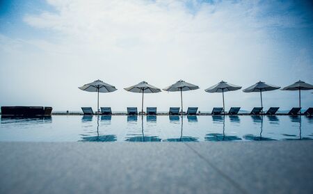 bed pool with umbrella with swimming pool foregroundの写真素材