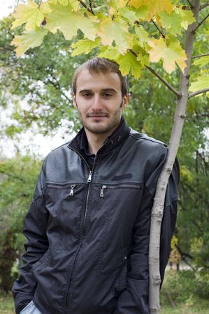 Young man standing near the autumn treeの写真素材