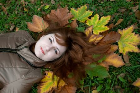 Portrait of a young beautiful ginger lying on the autumn leavesの写真素材