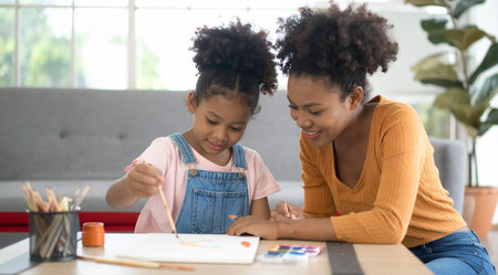 African american mother and daughter painting with watercolors at homeの素材