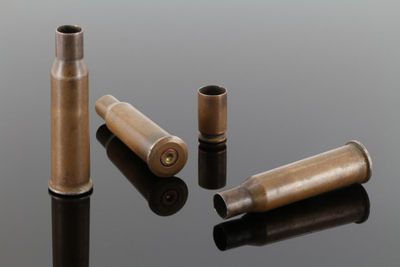 Old rifle and pistol bullet casings on a dark mirror background
