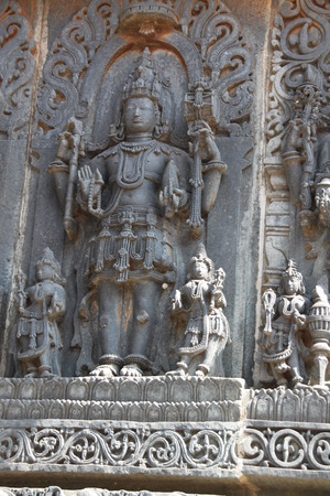 Beautiful carving of Lord Vishnu in the ancient temple at Bellur in India. The face is very calm and the devotees by his sideの写真素材