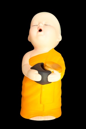 Doll clay baby monk with  alms bowl isolated on black backgroundの写真素材