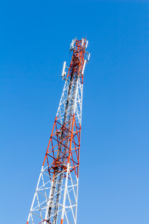 communication tower with antennas against blue sky background