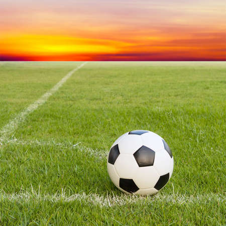 soccer ball on soccer field against sunset sky backgroundの写真素材