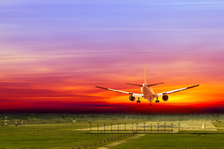 Commercial airplane landing on runway in airport at sunsetの写真素材