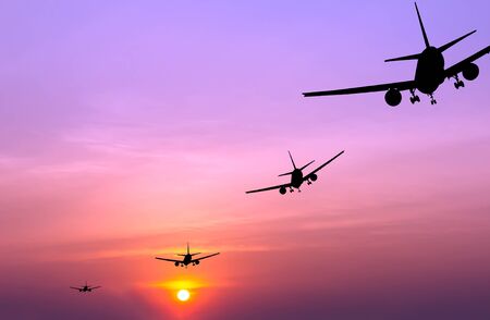 Silhouetted commercial airplane flying at sunset