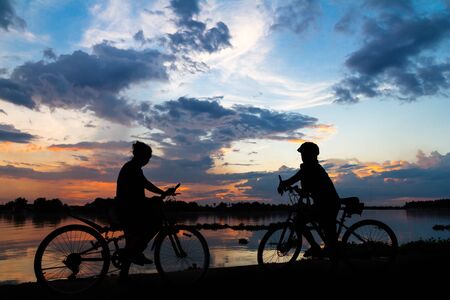 silhouette bike girl at sunset beside the river in countryside of Thailandの写真素材