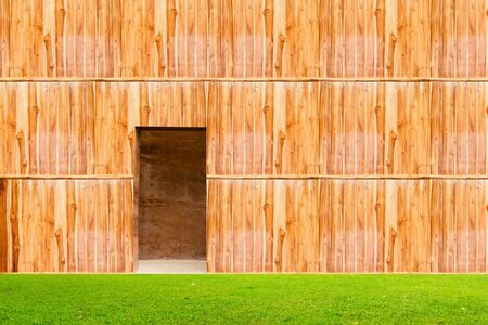 wooden wall with door and grass floor in front offの写真素材