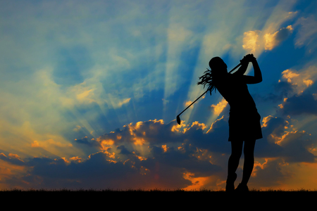 silhouette golfer playing golf during beautiful sunsetの写真素材
