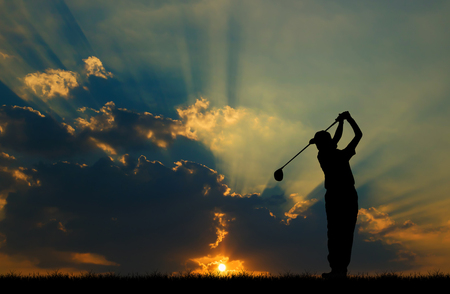 silhouette golfer playing golf during beautiful sunsetの写真素材