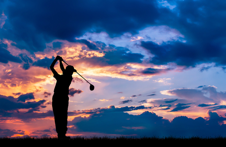 silhouette golfer playing golf during beautiful sunsetの写真素材