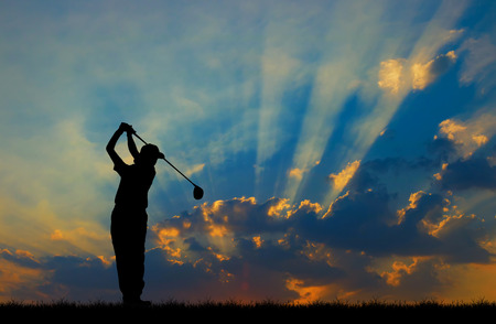 silhouette golfer playing golf during beautiful sunsetの写真素材