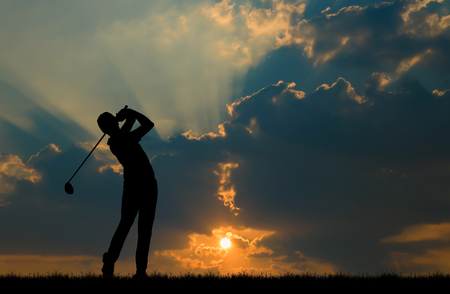 silhouette golfer playing golf during beautiful sunsetの写真素材