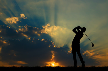 silhouette golfer playing golf during beautiful sunsetの写真素材