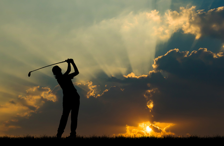 silhouette golfer playing golf during beautiful sunsetの写真素材