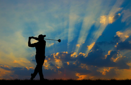 silhouette golfer playing golf during beautiful sunsetの写真素材