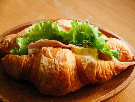 Croissant sandwich on wooden dishの写真素材