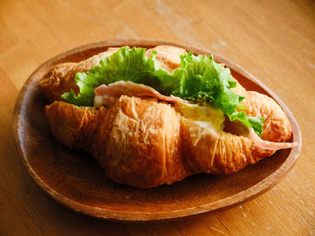 Croissant sandwich on wooden dishの写真素材