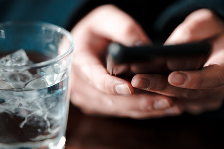 A hand operating a smartphone and a glassの写真素材