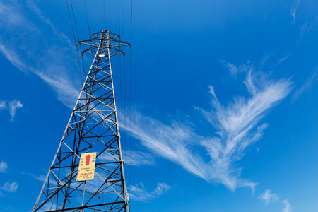 High voltage power line against a blue sky with white clouds and copy space