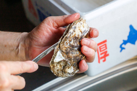 Oyster being cleaned by a woman's hand. Close-up.の写真素材