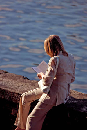 Young woman reading book outdoorsの写真素材