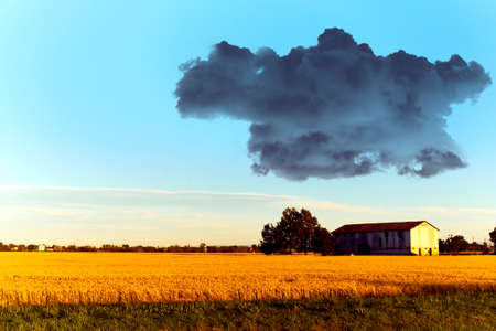 Black cloud over a country house in the sunの写真素材