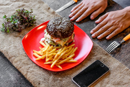 Hamburger and french fries in a red plate on the table