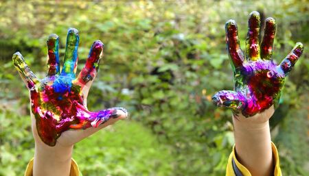 Kid hands with hands with different color paint on his palms