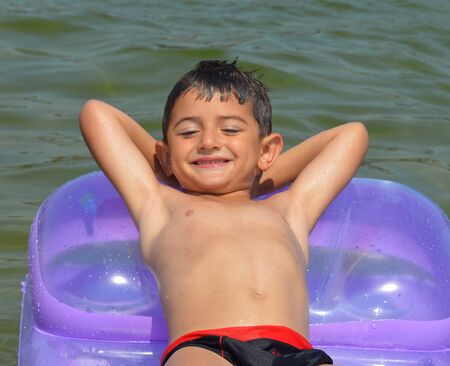 Boy on air mattress in seaの写真素材