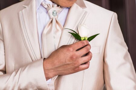 A groom putting on cuff-links as he gets dressed in formal wear .Groom's suitの写真素材