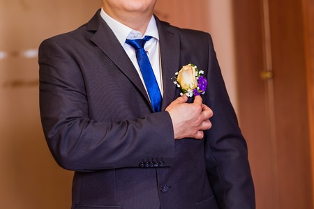 A groom putting on cuff-links as he gets dressed in formal wear .Groom's suitの写真素材