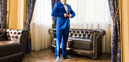 A groom putting on cuff-links as he gets dressed in formal wear .Groom's suitの写真素材